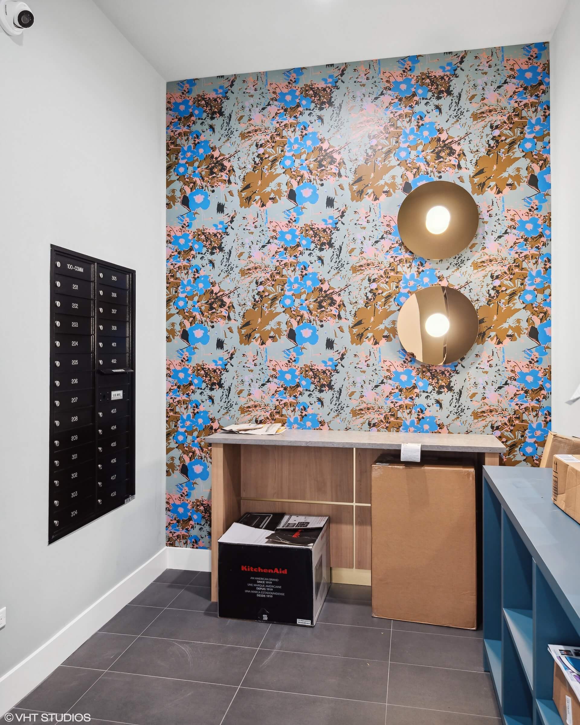 Package and mail room with designer wallpaper and custom light fixtures.