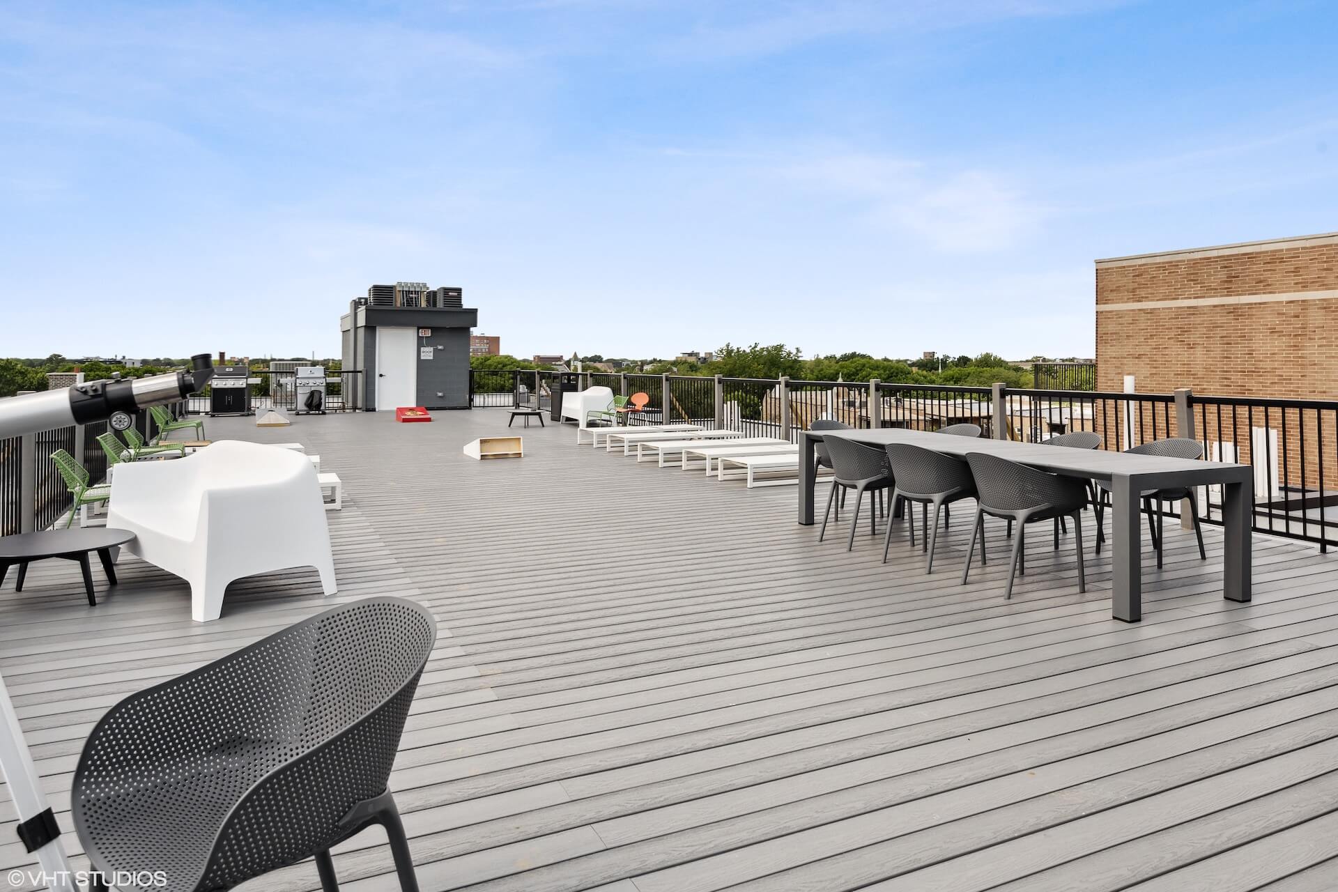 Private rooftop deck with grill station, lounge seating, a large table, telescopes, and corn hole games.