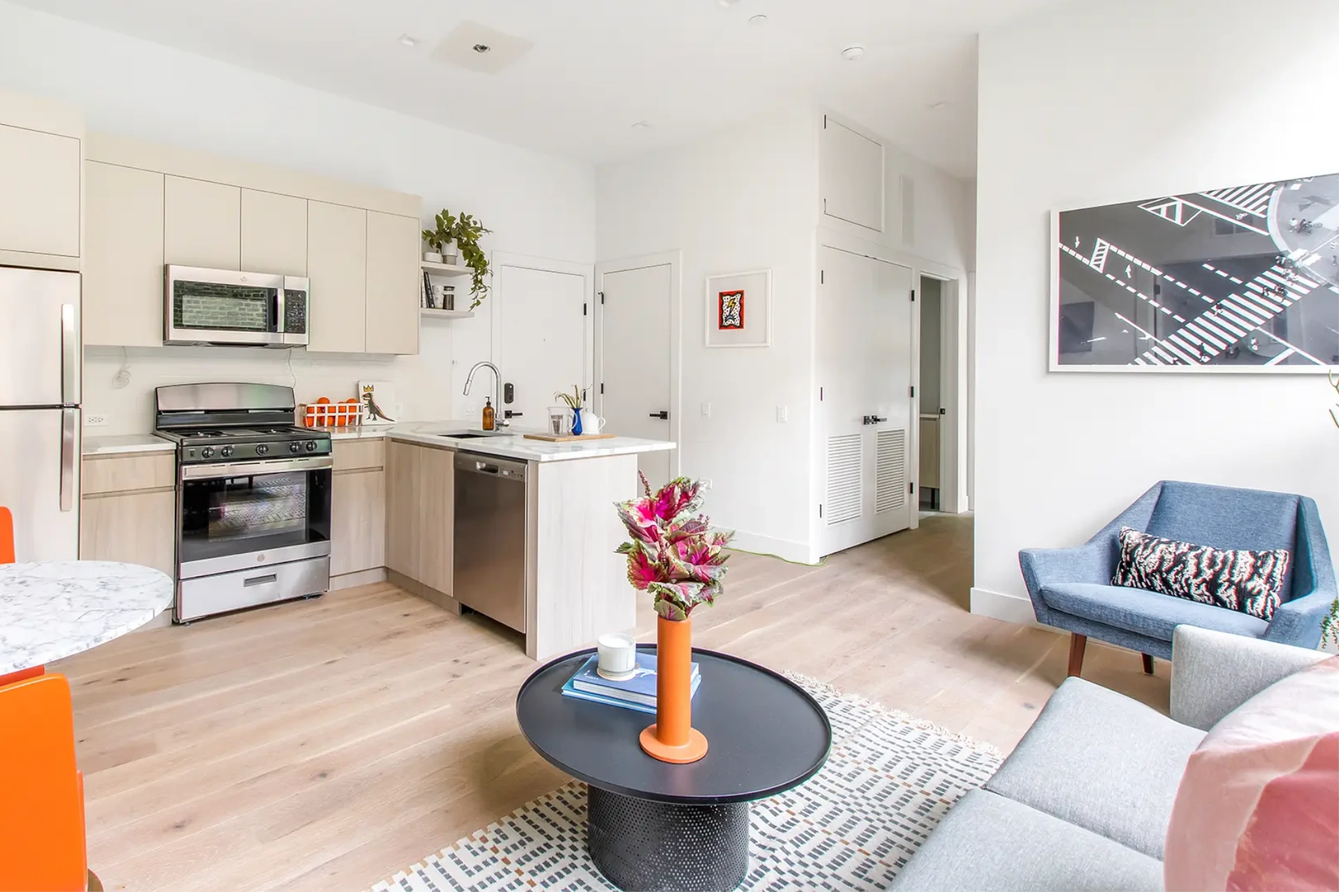 Open concept kitchen with white granite style countertops adjacent to living space with ample natural light.